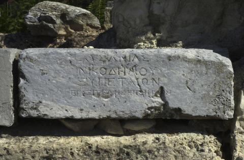 A rectangular block of marble with 4 lines of greek lettering