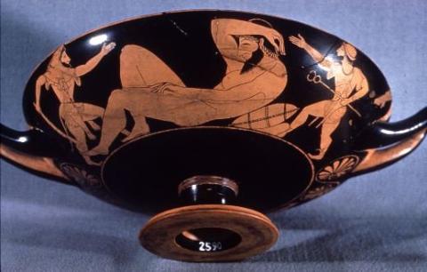 Herakles (left) sneaks up on the unconscious giant Alkyoneus (center), with Hermes (right) helping him. Herakles wears his lion skin and carries his club in his left hand. He gestures toward Alkyoneus with his right. Hermes carries his caduceus in his left hand and gestures toward Alkyoneus with his right. Alkyoneus lies with his feet toward Herakles and his right arm thrown over his face.