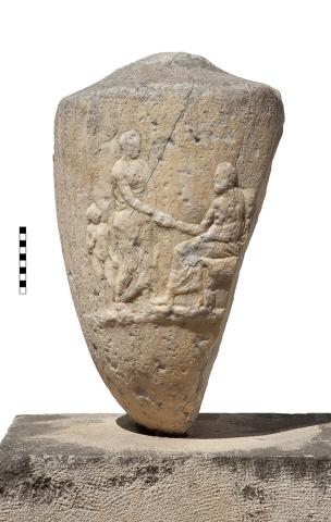 A large section of a marble vessel with a depiction of three figures, with badly worn Greek lettering above each figure's head.