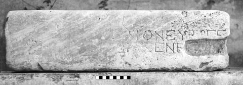 A rectangular block of marble with two lines of Greek lettering, preserved on the right side but worn away on the left side. A large notch is cut away from the right hand edge.