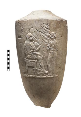 The main body of a vessel, decorated with a relief carving of two people, as well as a single word of Greek lettering