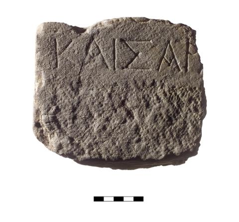 An square shaped chunk of marble with a single line of Greek lettering