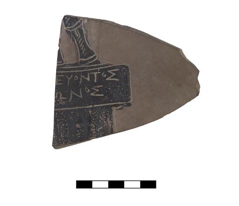 A roughly triangularly shaped clay fragment with part of two lines of Greek lettering and a part of a pedestal and figure