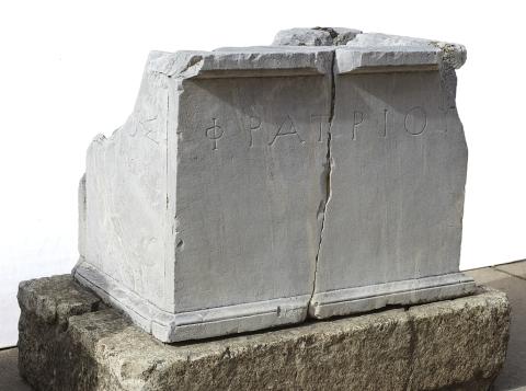 A large, plain marble altar with a single line of Greek lettering.