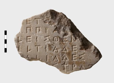 An irregularly shaped marble fragment containing fragments of six lines of Greek lettering