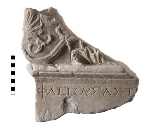 A triangular fragment of Pentelic marble, the top half of which is decorated in an Acanthus motif and the bottom half of which has a fragment of a line of Greek Lettering