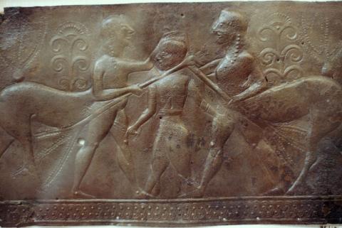 Caeneus (center) is stabbing a centaur (left) with a sword in his right hand. The centaur's left hand is on top of Caeneus' head; in his right hand he holds a tree trunk against Caeneus' neck. A second centaur, holding a tree trunk in his left hand, stands behind Caeneus (right). Both centaurs have human front legs and horse rear legs.