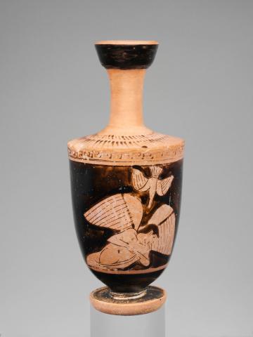 A nude youth with wings faces down his hands appear to be clasped on his chest, but the finish is damaged. Above him a bird flies, head down with beak pointed to the youth.