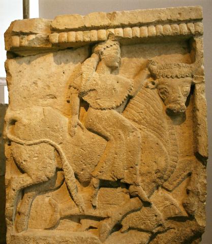 Europa, in right profile, sits sideways on the back of a bull. She wears a chiton and wrap; her hair hangs down her back, gathered at the neck. The bull's head is turned to look at the viewer. Europe grasps its right horn with her left hand. Below the bulls hooves are two dolphins.