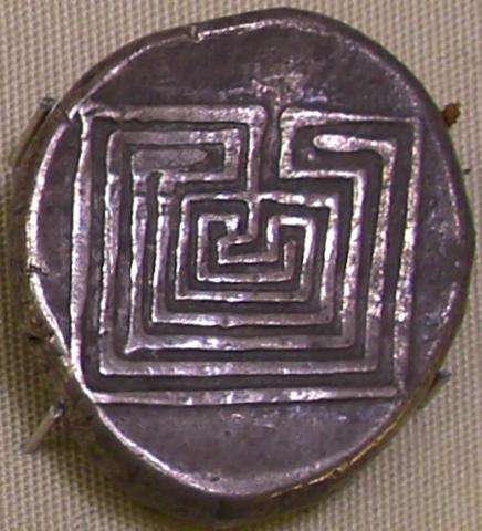 Tarnished round silver coin stamped with the image of a square labyrinth