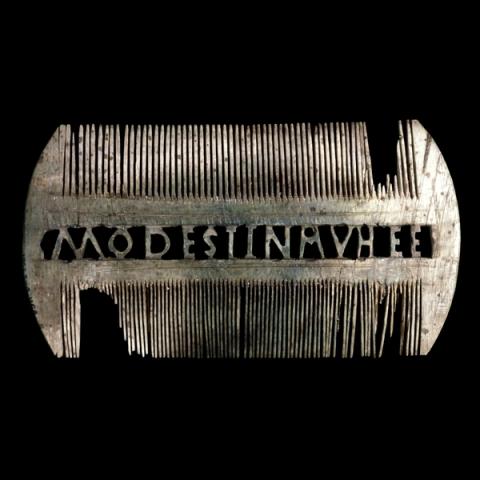 Double-sided ivory comb. The center spine has been carved out to read MODESTINA VHEE.