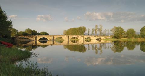 river in summer time with old stone bridge