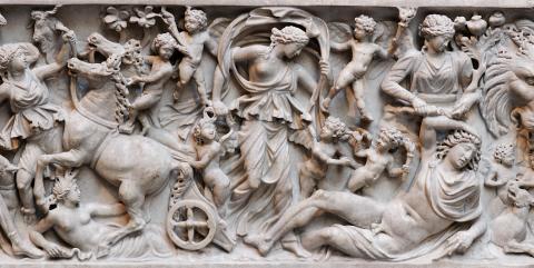 Carved panel from the side of a Roman sarcophagus. Selene, steps down from her chariot. At her feet lies Endymion.  A woman stands over him, holding a bunch of poppies in the crook of her left arm. In her right hand she pours something from a small bottle over Endymion. 