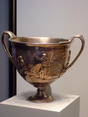 Two-handled silver cup with relief decoration depicting a scene from Odyssey 11.26-42. Odysseus is shown holding a sword up in his right hand. He looks to his left toward a tree. At Odysseus's feet lies the ram he has just sacrificed to summon the dead. To Odysseus's right sits the spirit of the seer Teiresias sits on a rock.