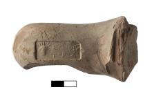 A clay handle with a stamp containing two lines of Greek lettering and a figure's head