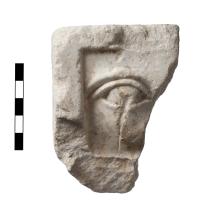 A fragment of marble showing a relief fragment of a relief sculpture depicting an eye.