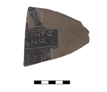 A roughly triangularly shaped clay fragment with part of two lines of Greek lettering and a part of a pedestal and figure