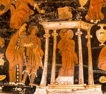 Niobe stands inside a smalle temple. She is dressed in a peplos with himation wrapped around her shoulders and covering her head. The temple is depicted by four Ionic columns and a low roofline decorated by antefixes at the corners. To the left, outside the temple stands an old man wearing ankle length robes and a diadem. he is supported by a younger man dresses in a cal-length tunic and cloak. 