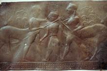 Caeneus (center) is stabbing a centaur (left) with a sword in his right hand. The centaur's left hand is on top of Caeneus' head; in his right hand he holds a tree trunk against Caeneus' neck. A second centaur, holding a tree trunk in his left hand, stands behind Caeneus (right). Both centaurs have human front legs and horse rear legs.