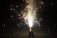 A rectangular canister sits on concrete and shoots sparks into the air.
