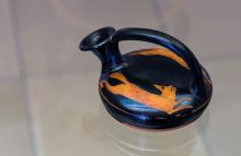Attic red-figure askos. The spout is pointing left the side of the body visible shows a fox with bushy tail fleeing right. It looks back over its shoulder at the dog (not pictured) that is chasing it.