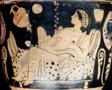 Danaë reclines on a bed draped with a patterned sheet. Her hair is arranged up on the back of her head and covered with a net or cloth. She wears a cloth drape open in front exposing her abdomen. Zeus in the form of rain falls on her abdomen.