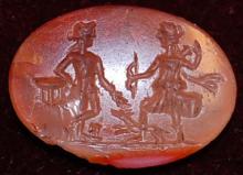 Pink-red chalcedony stone engraved with an image of Apollo leaning on a tripod, approached by Artemis, wearing a short tunic and carrying a bow in her right hand while pulling an arrow from her quiver with her left. A dog runs alongside Artemis