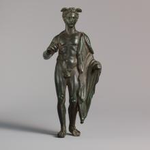 He stands with his weight resting on the right leg, with the left foot drawn back.