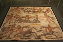 Mosaic depicting the battle between the Lapiths and Centaurs. The mosaic is laid out in three rows. Left to right, bottom row: a man grasps a centaur by the hair and thrusts forward with a spear held in his right hand. Another centaur appears lower right facing an unseen opponent. Middle row: a man attacks a centaur attempting to capture woman. Another man reaches toward the woman as if to help her escape. Top row: A man attacks a centaur who holds a woman by her arm. Another man appears to flee right.  