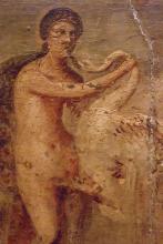 Leda stands on the left holding a swan by the neck with her left hand. The swan's beak hovers near Leda's mouth. Its wings stretch out behind it to the right of the fresco.