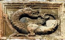 a stone relief sculpture of a dragon eating its tail