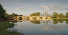 river in summer time with old stone bridge
