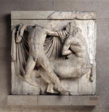 A centaur appears to be fleeing right, but is held back by a man facing full front. The centaur's right arm is twisted behind his back, as if reaching for something. His left arm is raised, but is missing from the bicep, as is the centaur's head. The man appears to be grasping the centaur by the back of the head with his left hand. The man's right arm is missing from the bicep, but is raised as if about to strike. His head is also missing, and he is nude except for a cloak draped behind him.